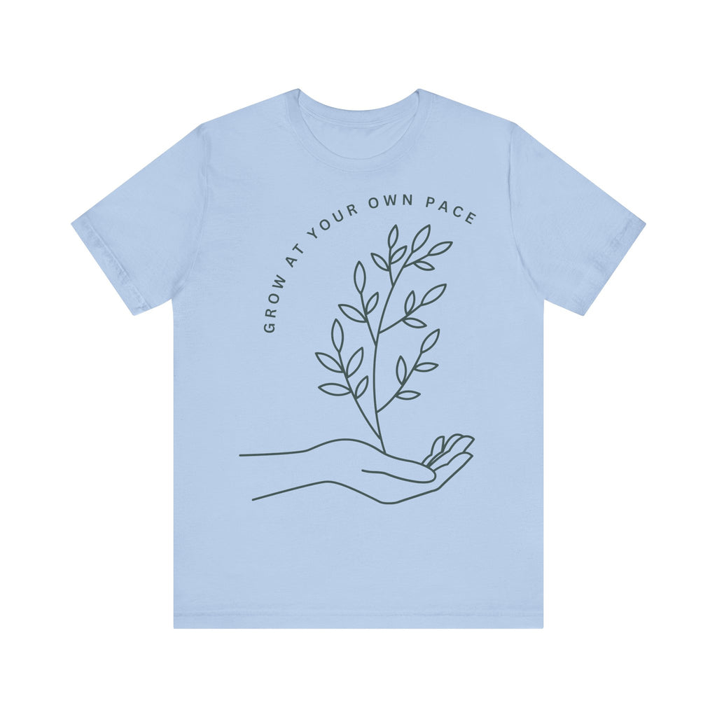 Minimal botanical print T-shirt with "Grow At Your Own Pace" slogan, featuring green leafy design on soft fabric.