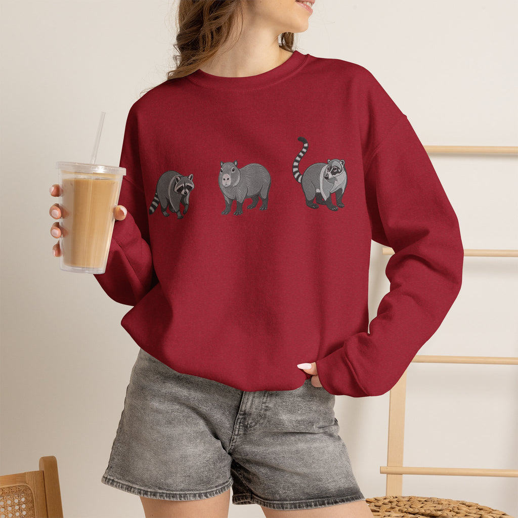 Wildlife Trio graphic sweatshirt featuring raccoon, capybara, and coati designs from Wyldelife Collection by Printify.
