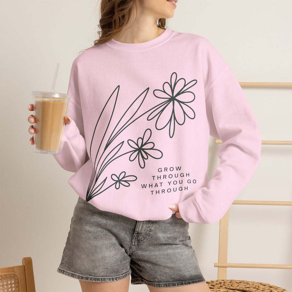 Pink crewneck sweatshirt with floral design and motivational quote "Grow Through What You Go Through" by Printify.