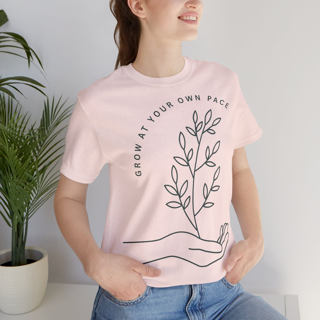 Minimal botanical print t-shirt with "Grow At Your Own Pace" slogan, featuring green plant illustrations on a casual Printify tee.
