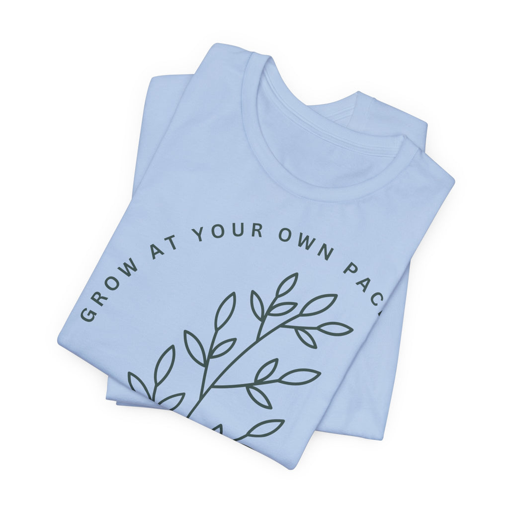 Minimal botanical T-shirt with "Grow At Your Own Pace" print, featuring green plant illustrations on a white fabric.