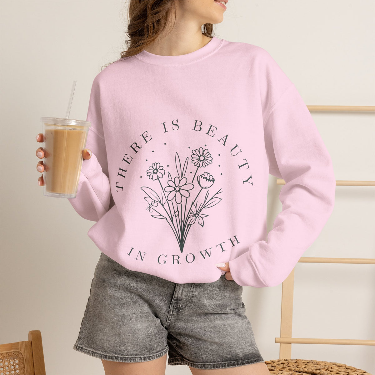 Cream crewneck sweatshirt with floral minimalist design and the phrase "There Is Beauty in Growth" printed on the front.