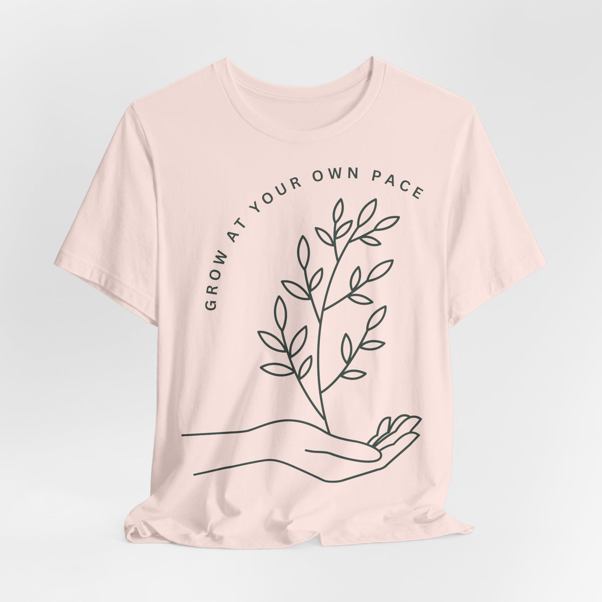 Minimal botanical print T-shirt from Printify with "Grow At Your Own Pace" slogan, featuring a simple plant illustration.