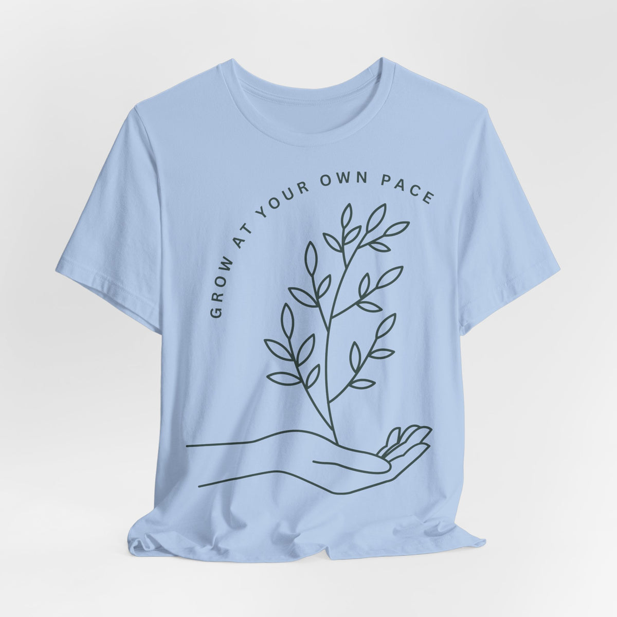 Minimal botanical print T-shirt with "Grow At Your Own Pace" slogan, designed by Printify, featuring green plant illustrations.