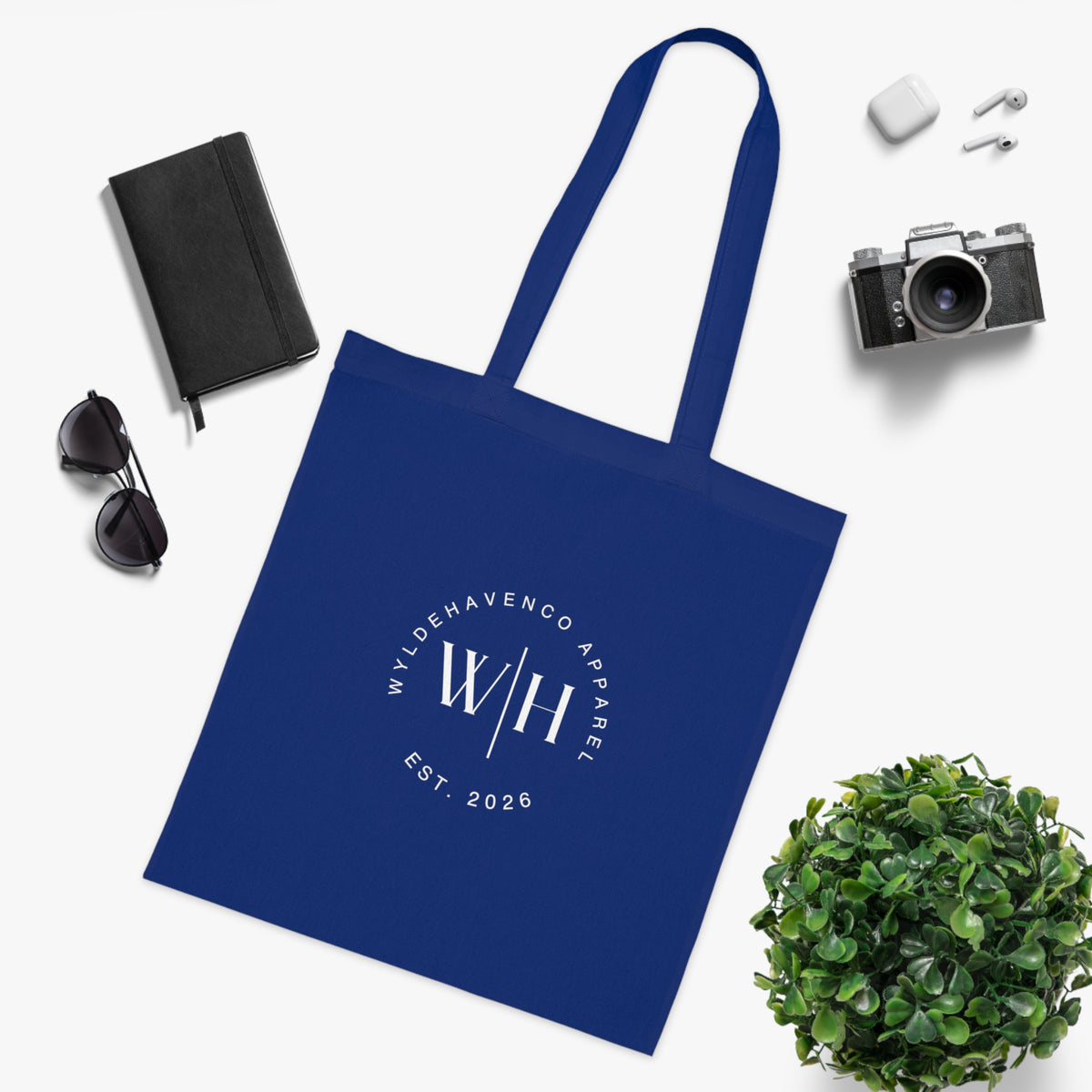 White canvas tote bag with black monogram circle and WH logo, featuring sturdy cotton handles and spacious interior.