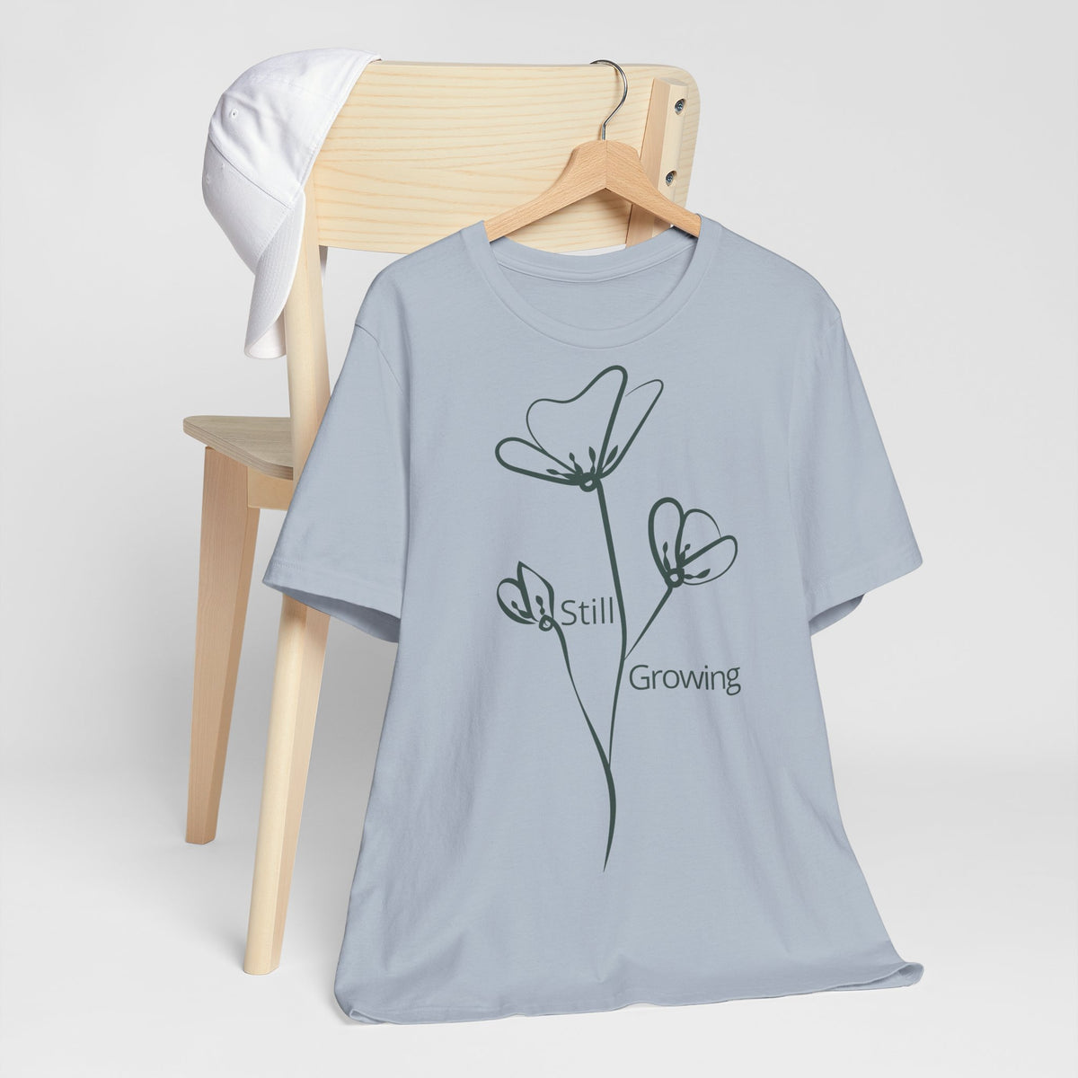 Still Growing Floral T-Shirt by Printify featuring a minimalist inspirational design with vibrant floral artwork on a casual tee