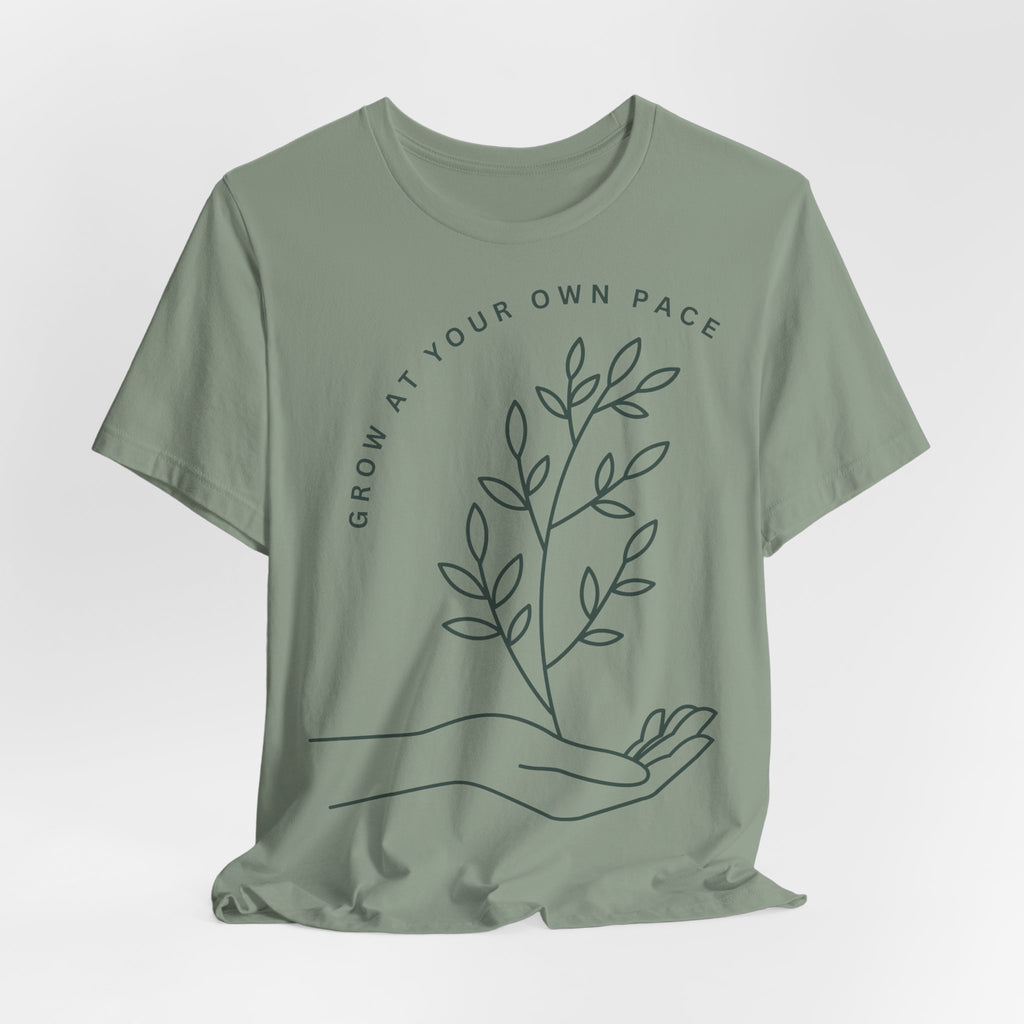 Minimal botanical Printify T-shirt with "Grow At Your Own Pace" slogan, featuring green plant illustrations on a comfortable fabric.