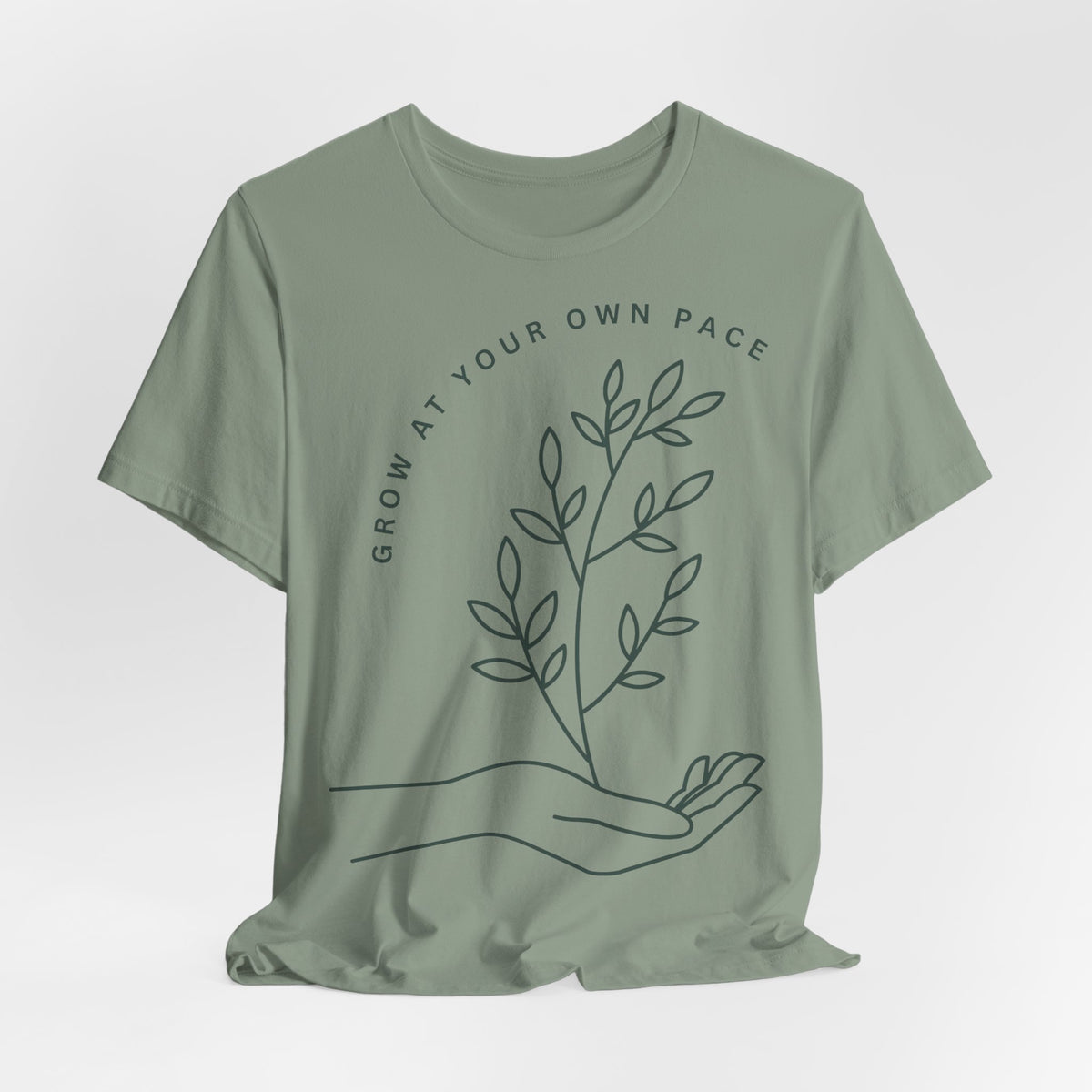 Minimal botanical Printify T-shirt with "Grow At Your Own Pace" slogan, featuring green plant illustrations on a comfortable fabric.