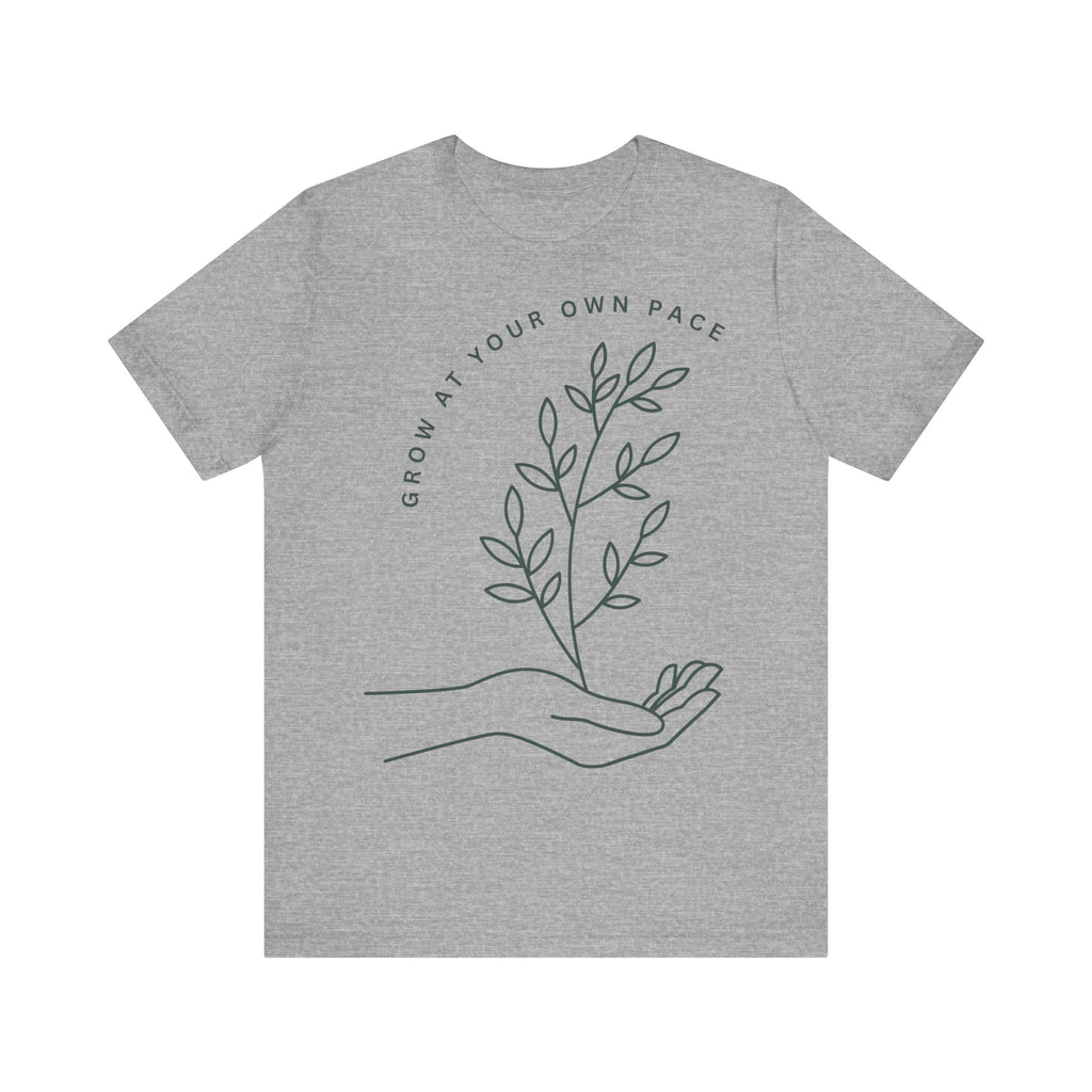 Minimal botanical print T-shirt with "Grow At Your Own Pace" slogan, featuring leafy design on a casual Printify T-shirt.