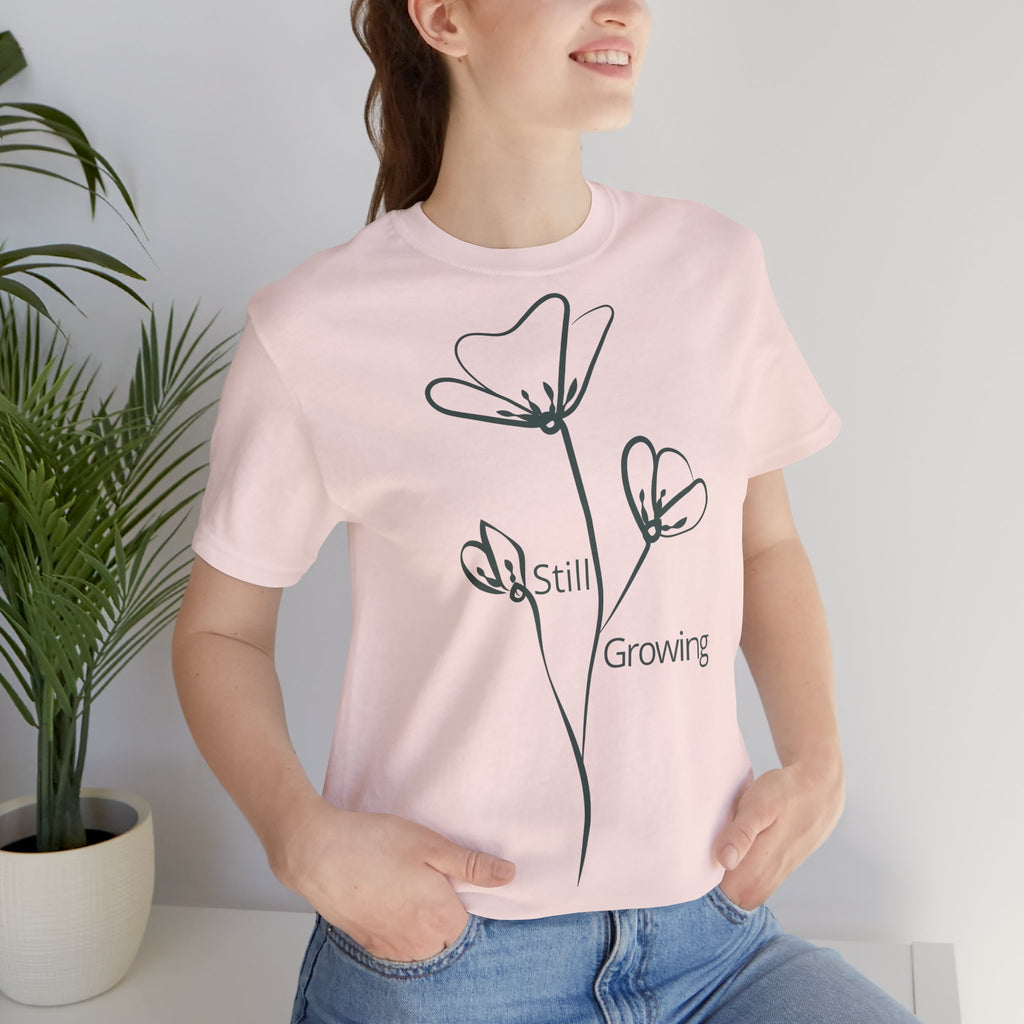 Still Growing Floral T-Shirt by Printify featuring a minimalist floral design, casual fit, and inspiring message on soft fabric.