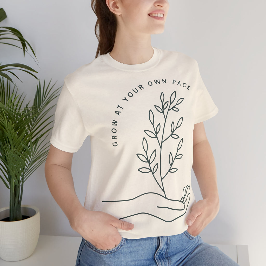 Minimal botanical print T-shirt with "Grow At Your Own Pace" slogan by Printify, featuring a green plant design on soft fabric.