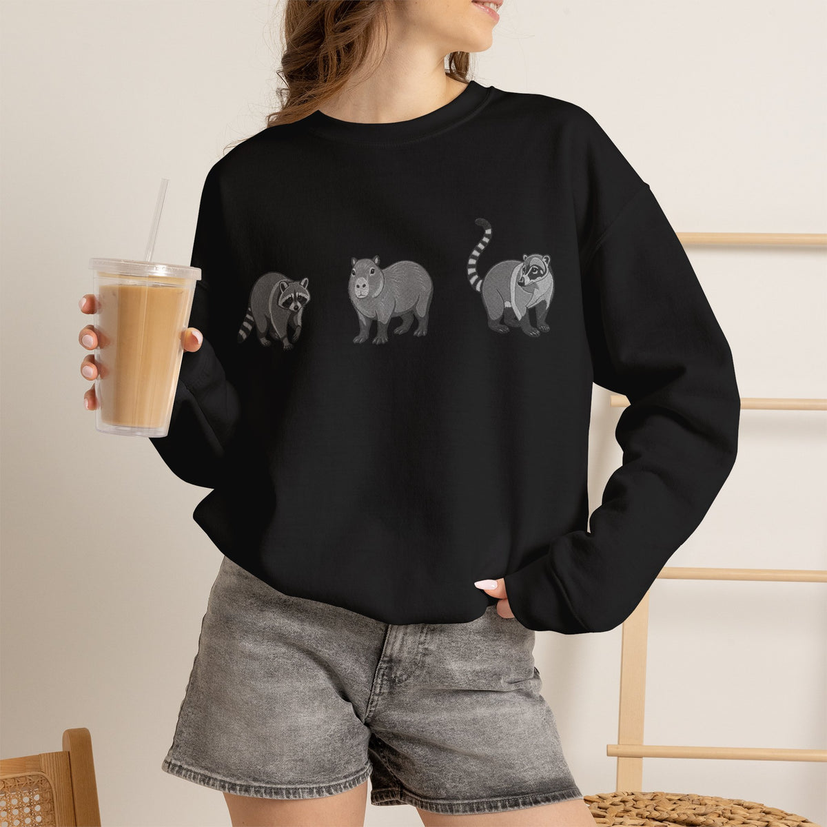 Wildlife Trio graphic sweatshirt featuring raccoon, capybara, and coati images from Wyldelife Collection by Printify.