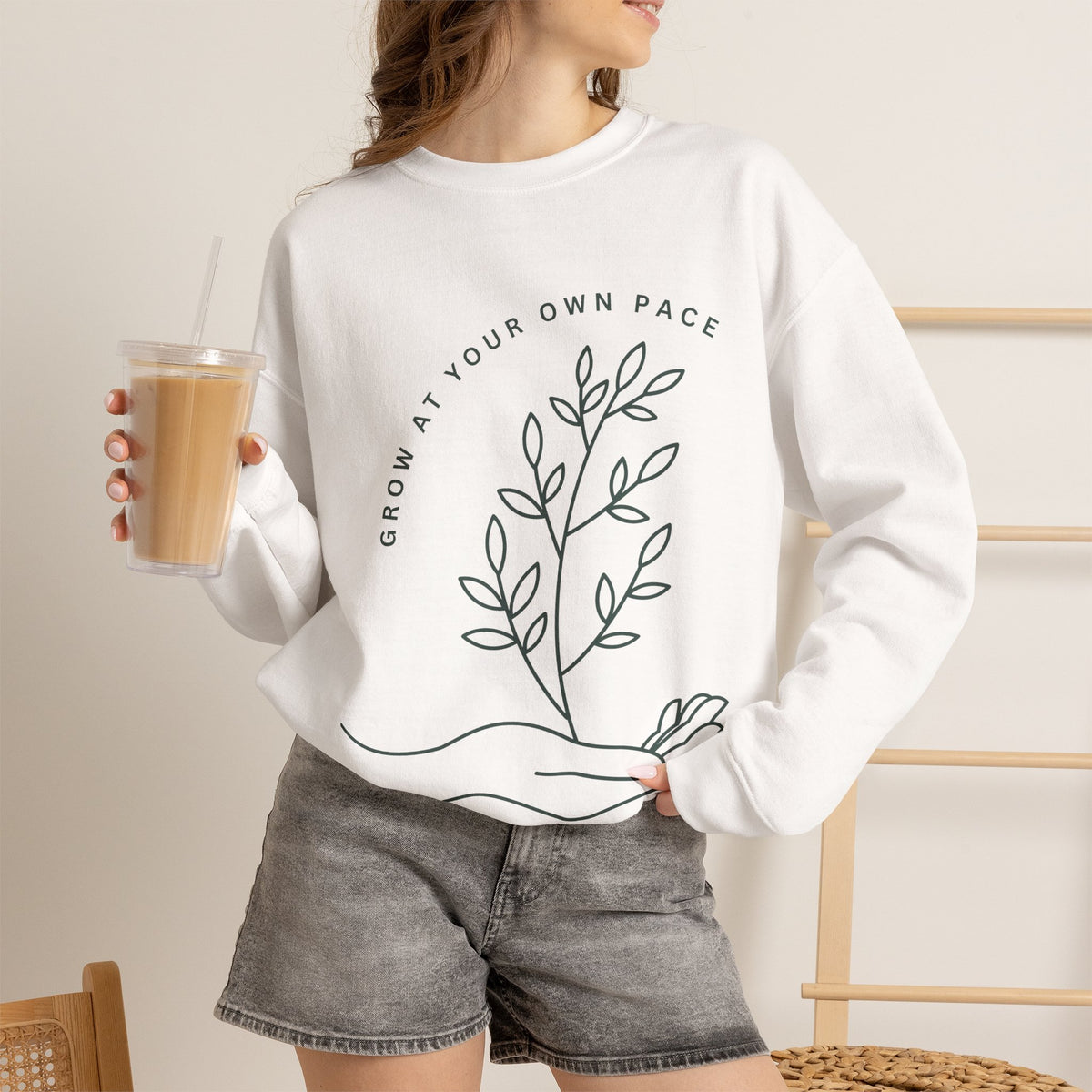 Printify Grow At Your Own Pace minimalist line art crewneck sweatshirt displayed on a hanger, showcasing simple and comfortable design.
