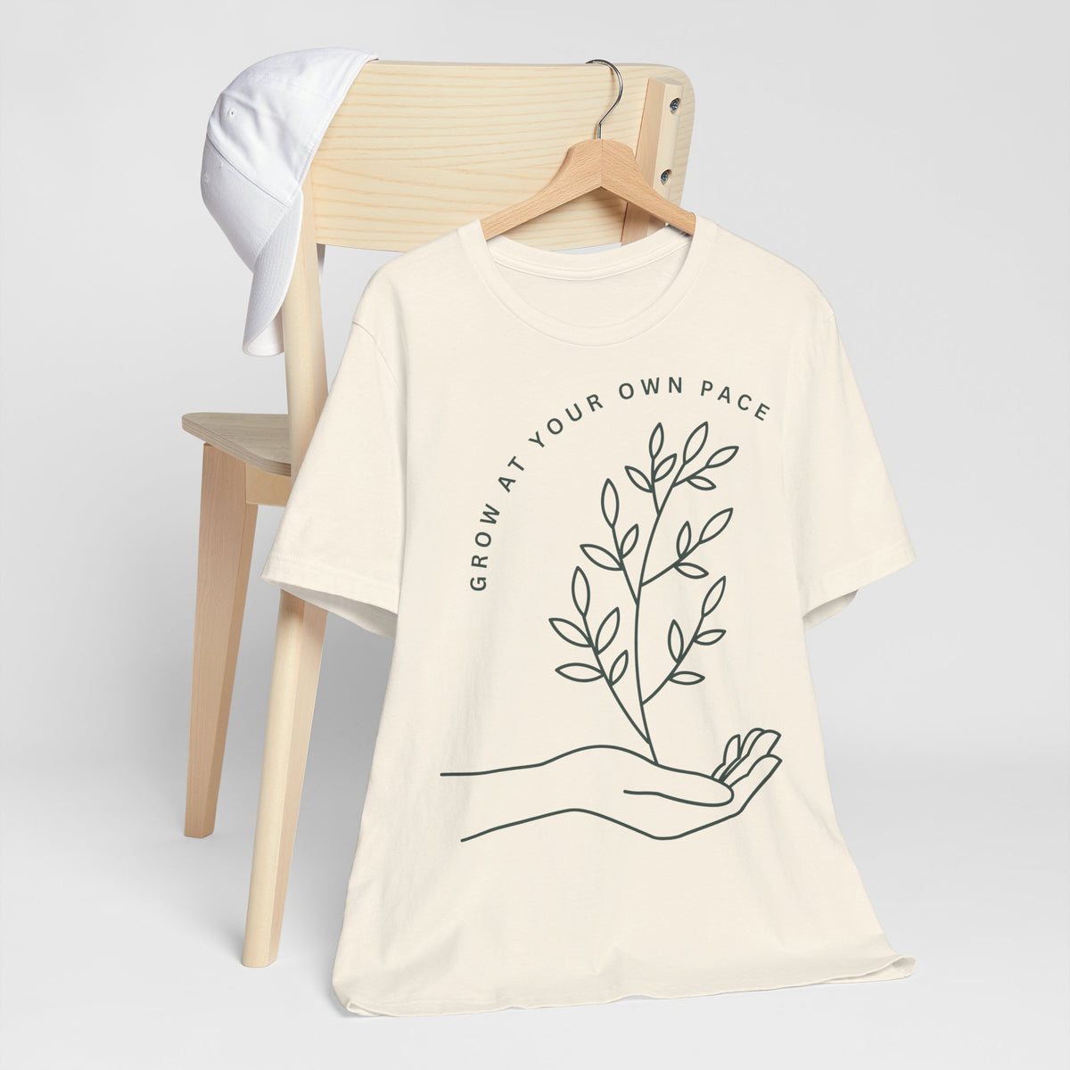 Minimal botanical print T-shirt by Printify featuring "Grow At Your Own Pace" slogan on soft cotton fabric.