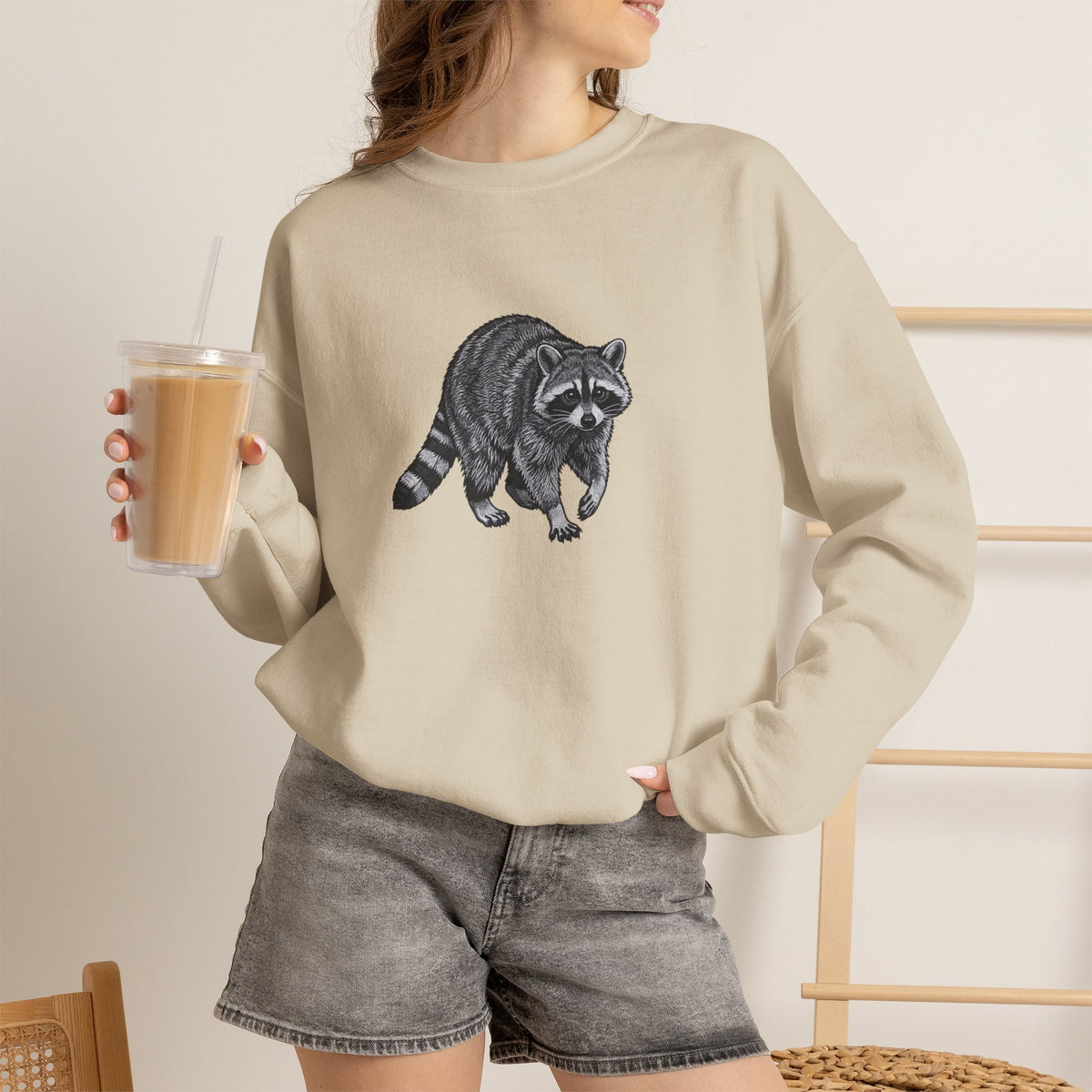 Gray sweatshirt featuring a detailed raccoon graphic from the Wyldelife Collection by Printify, showcasing wildlife art design.
