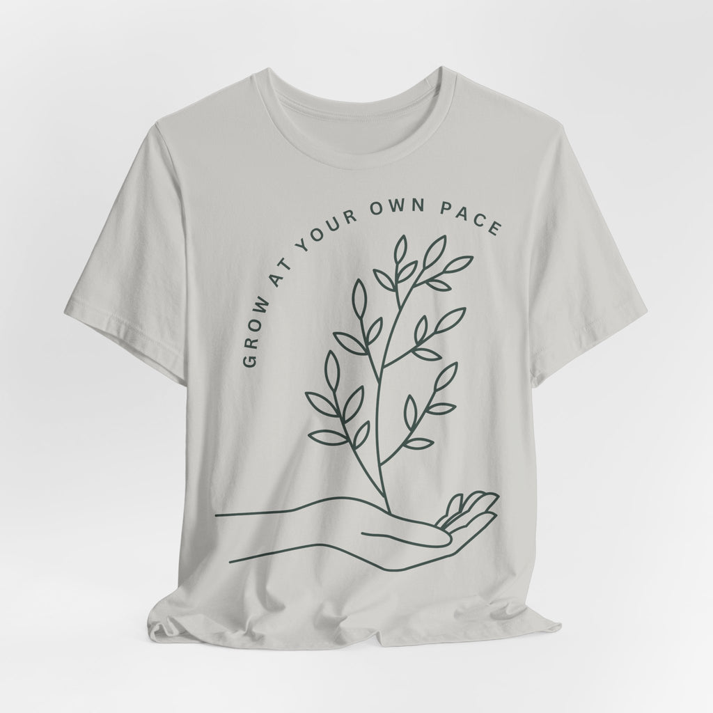 Minimal botanical Printify T-shirt featuring "Grow At Your Own Pace" slogan on soft, casual fabric.