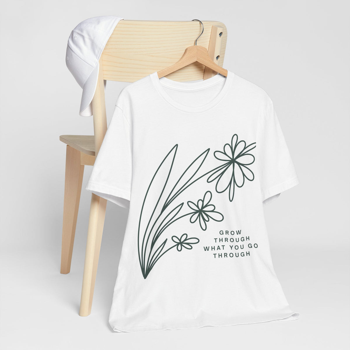 Floral inspirational graphic T-shirt with "Grow Through What You Go Through" message, designed by Printify, worn on a model.