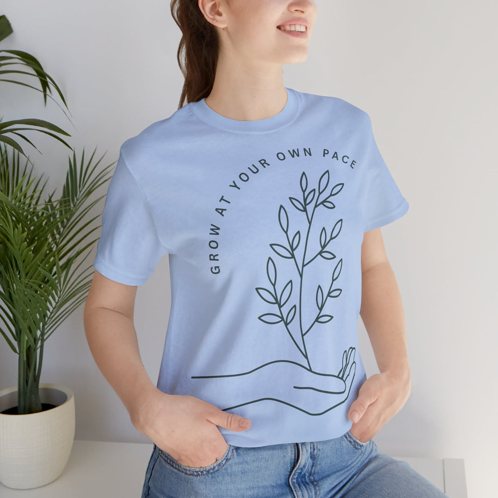 Minimal botanical print T-shirt from Printify featuring "Grow At Your Own Pace" slogan on a soft fabric tee.