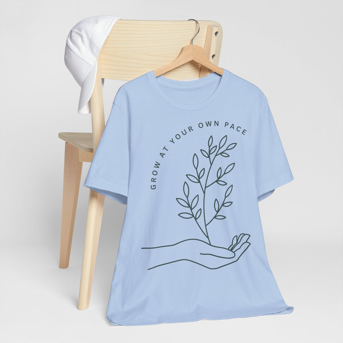 Minimal botanical print T-shirt from Printify with "Grow At Your Own Pace" slogan, featuring green plant illustrations on soft fabric.