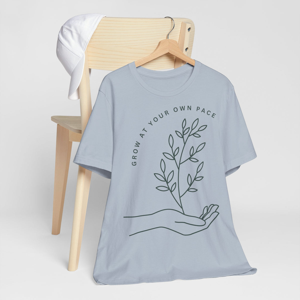 Minimal botanical print T-shirt with "Grow At Your Own Pace" slogan, designed by Printify, showing a casual, comfortable fit.