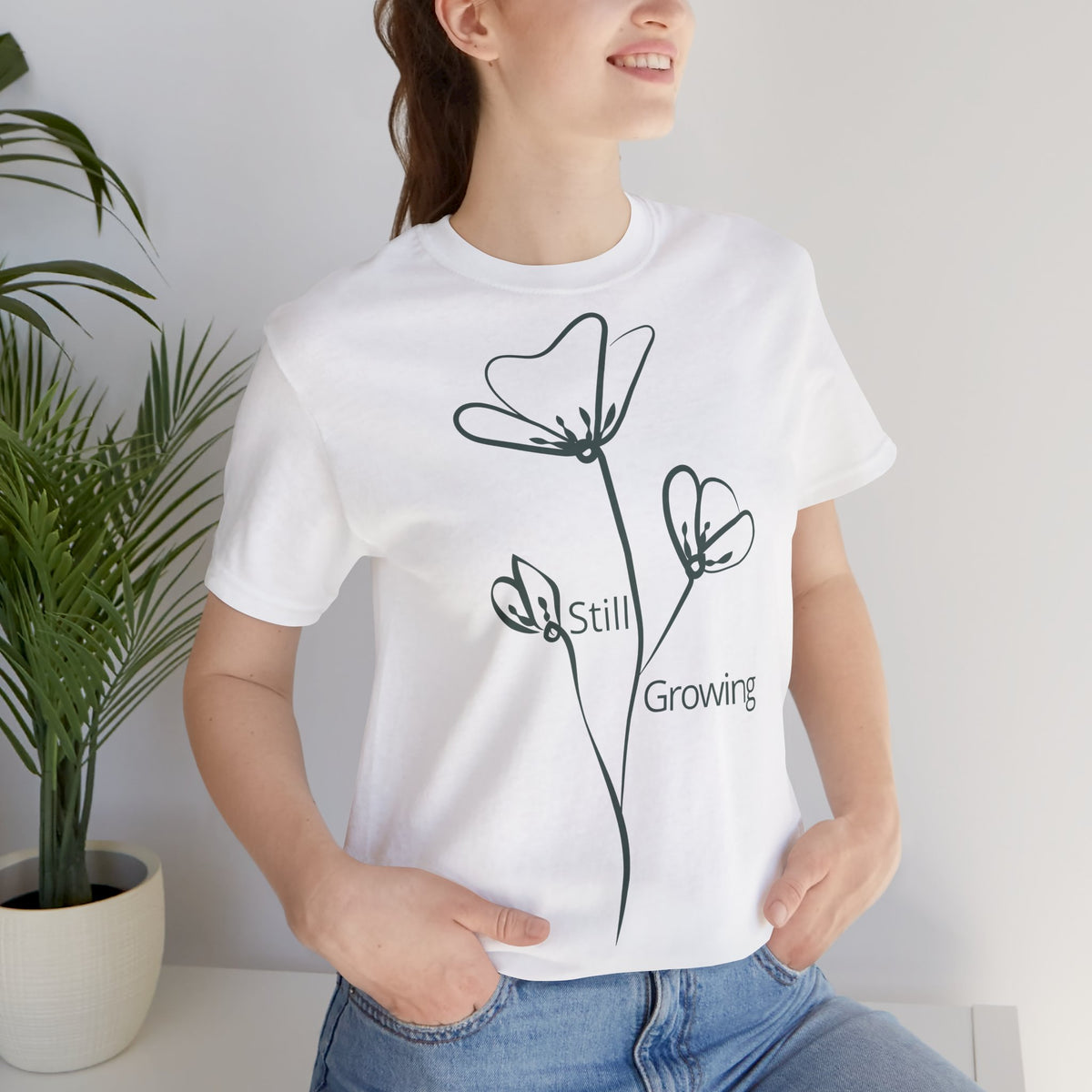 Still Growing Floral T-Shirt by Printify featuring a minimalist floral design and inspirational quote on a casual cotton tee.