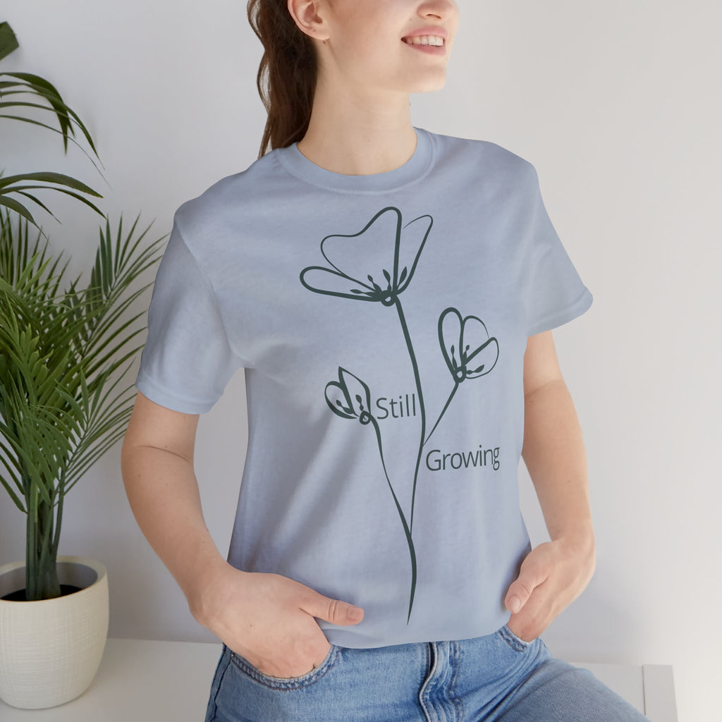 Still Growing Floral T-Shirt by Printify featuring a minimalist floral design on a casual, inspirational cotton tee.