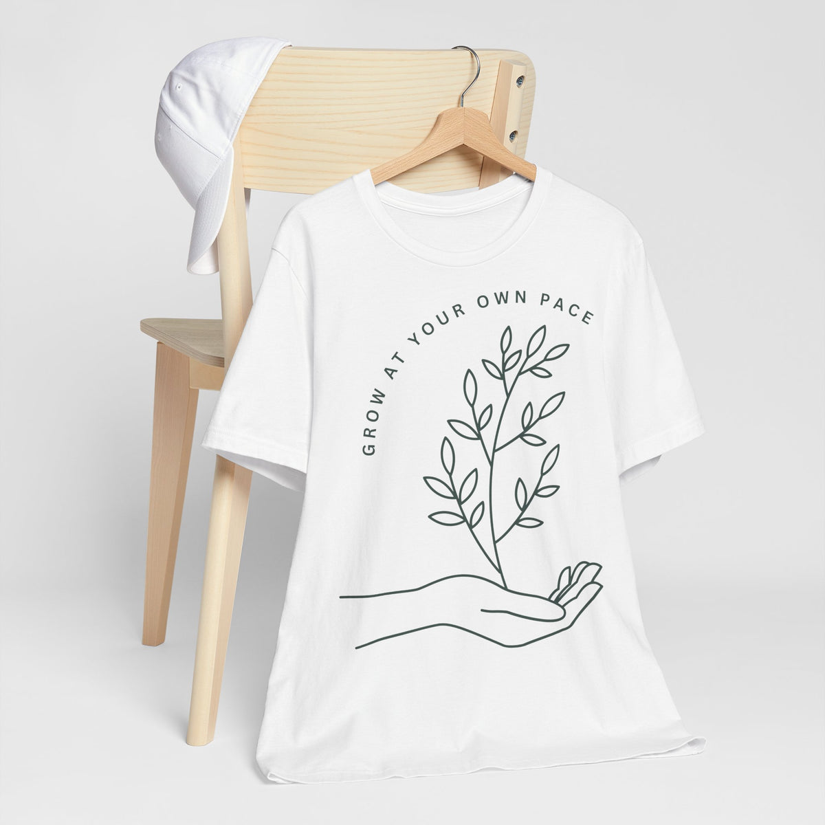 Minimal botanical print T-shirt from Printify featuring "Grow At Your Own Pace" slogan on soft fabric.