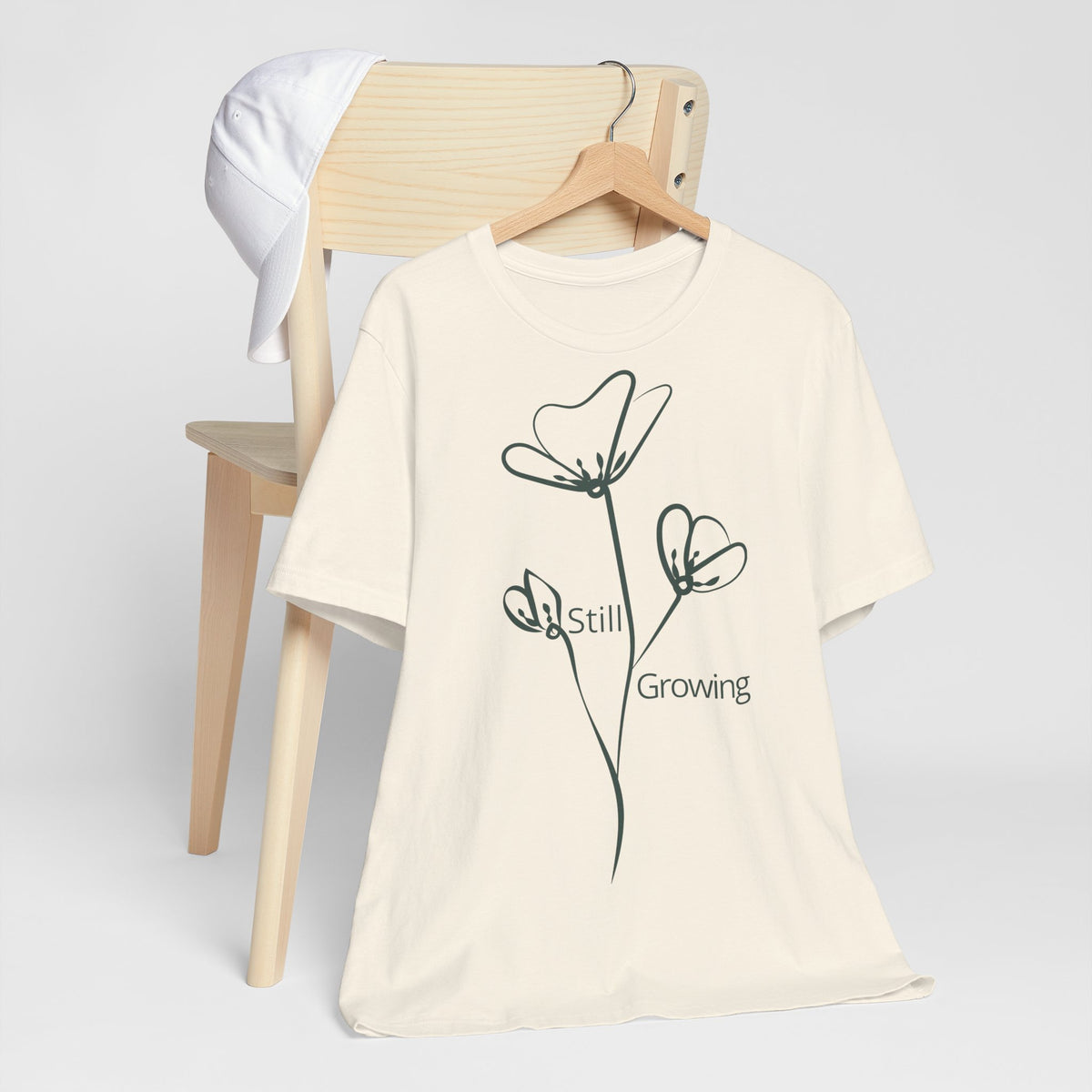 Still Growing Floral T-Shirt by Printify featuring a minimalist floral design on a casual inspirational tee.
