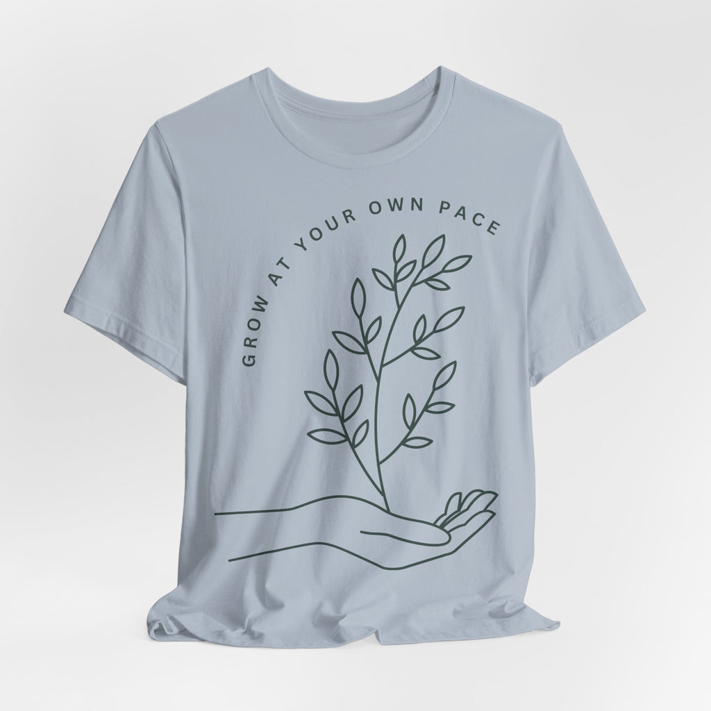 Minimal botanical t-shirt by Printify featuring "Grow At Your Own Pace" slogan on a soft fabric tee.